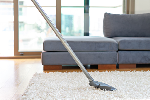 Photograph of a long metal dry carpet cleaning device on a white rug